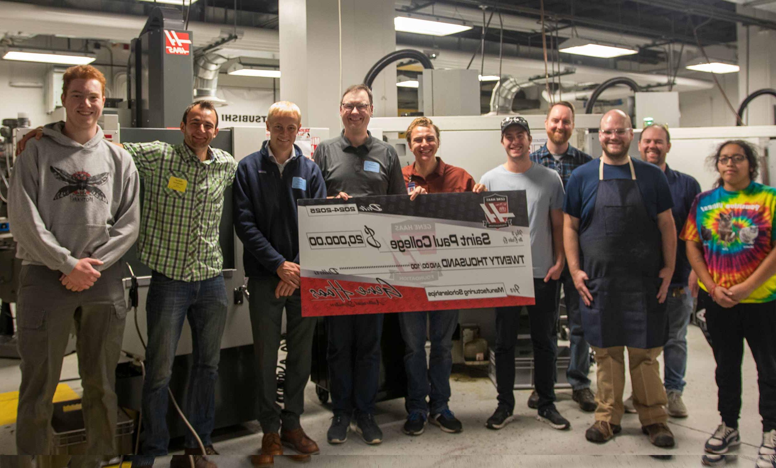 CNC students and faculty with representative from the Gene Haas foundation presenting a large check for $20,000 in the CNC lab